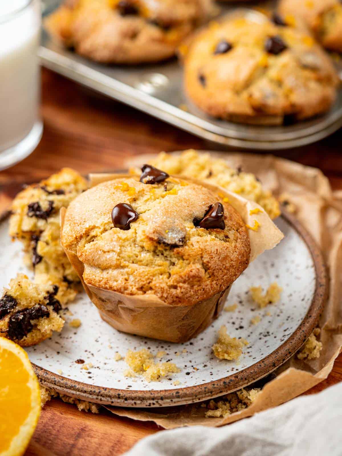 orange chocolate chip muffin on a plate with orange chocolate chip muffins in the background