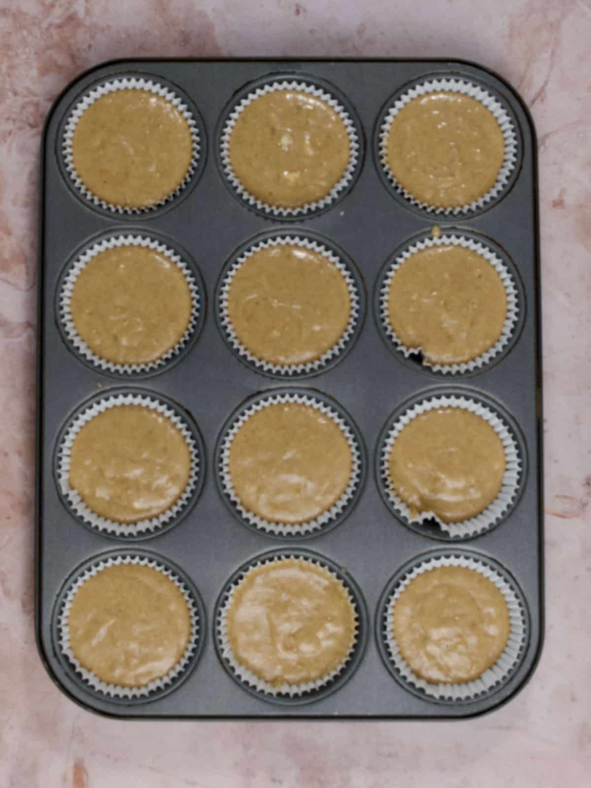 banana spice cake batter in cupcake liners in a cupcake pan
