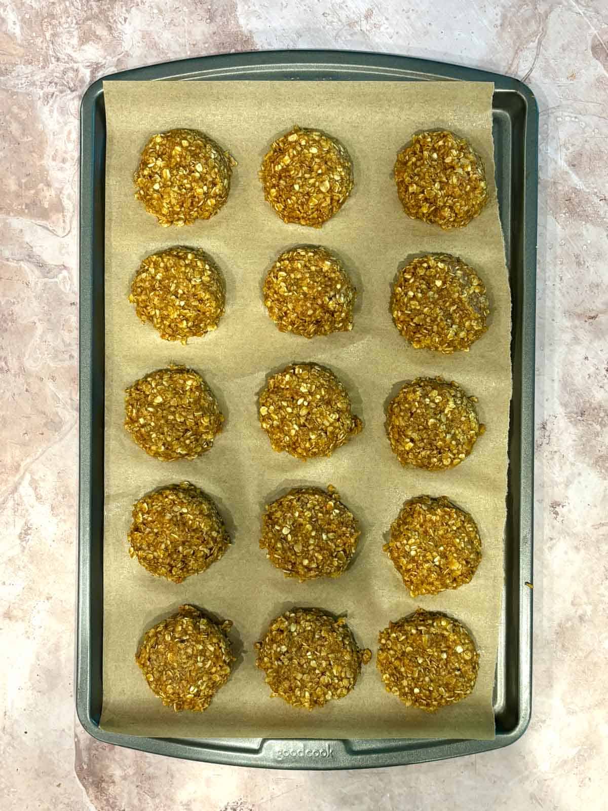 Pumpkin cookies on a cookie sheet with parchment paper.