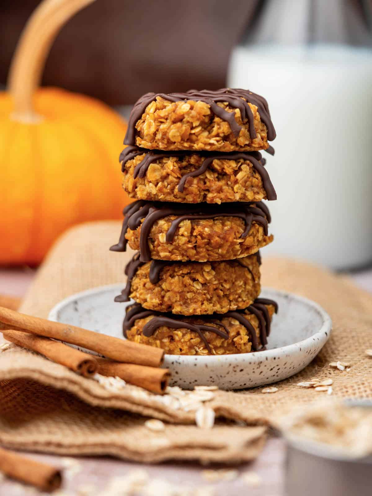 Stack of pumpkin cookies on a plate with milk in the background.