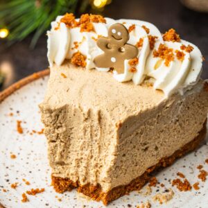 A slice of gingerbread cheesecake with whipped cream on a plate.