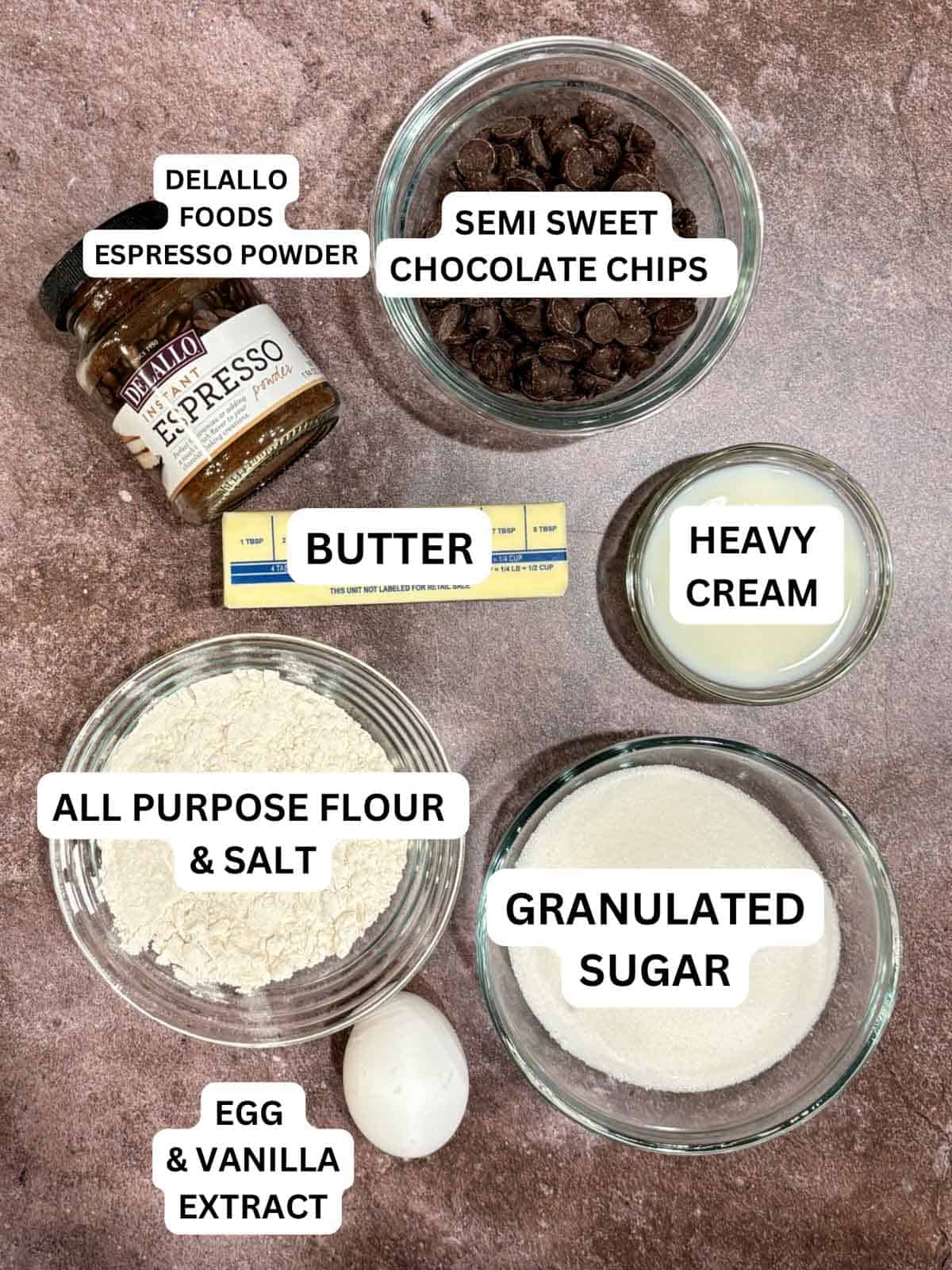 Ingredients used for espresso chocolate cookies. Flour, chocolate, sugar, egg, vanilla, espresso powder, butter, and powdered sugar.