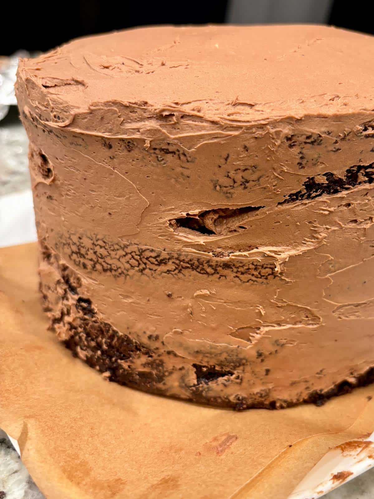 Three layers of chocolate cake with a crumb coat of chocolate mousse.