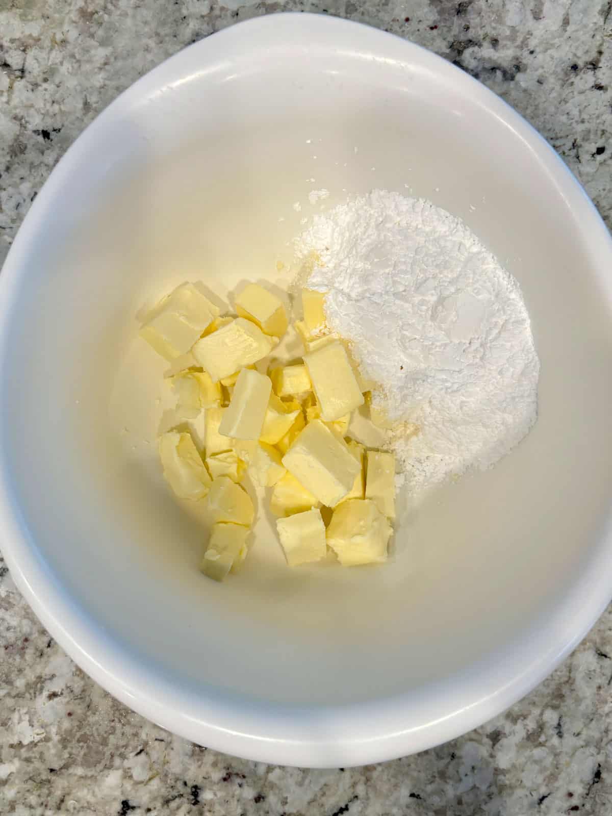 White bowl with butter and powdered sugar in it on the counter.