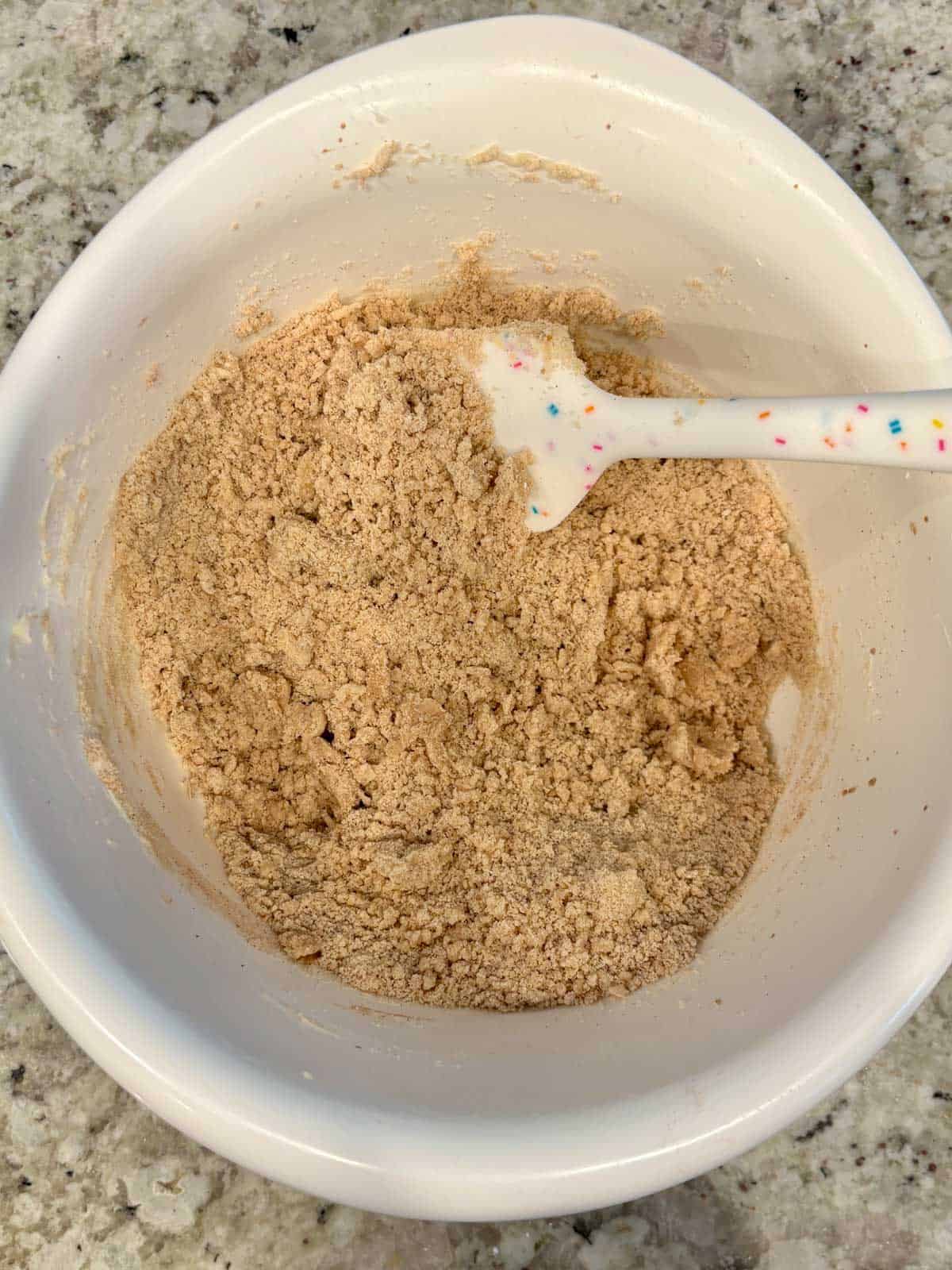 A white bowl with butter, sugar, flour, and cinnamon in it ready to be mixed into dough.