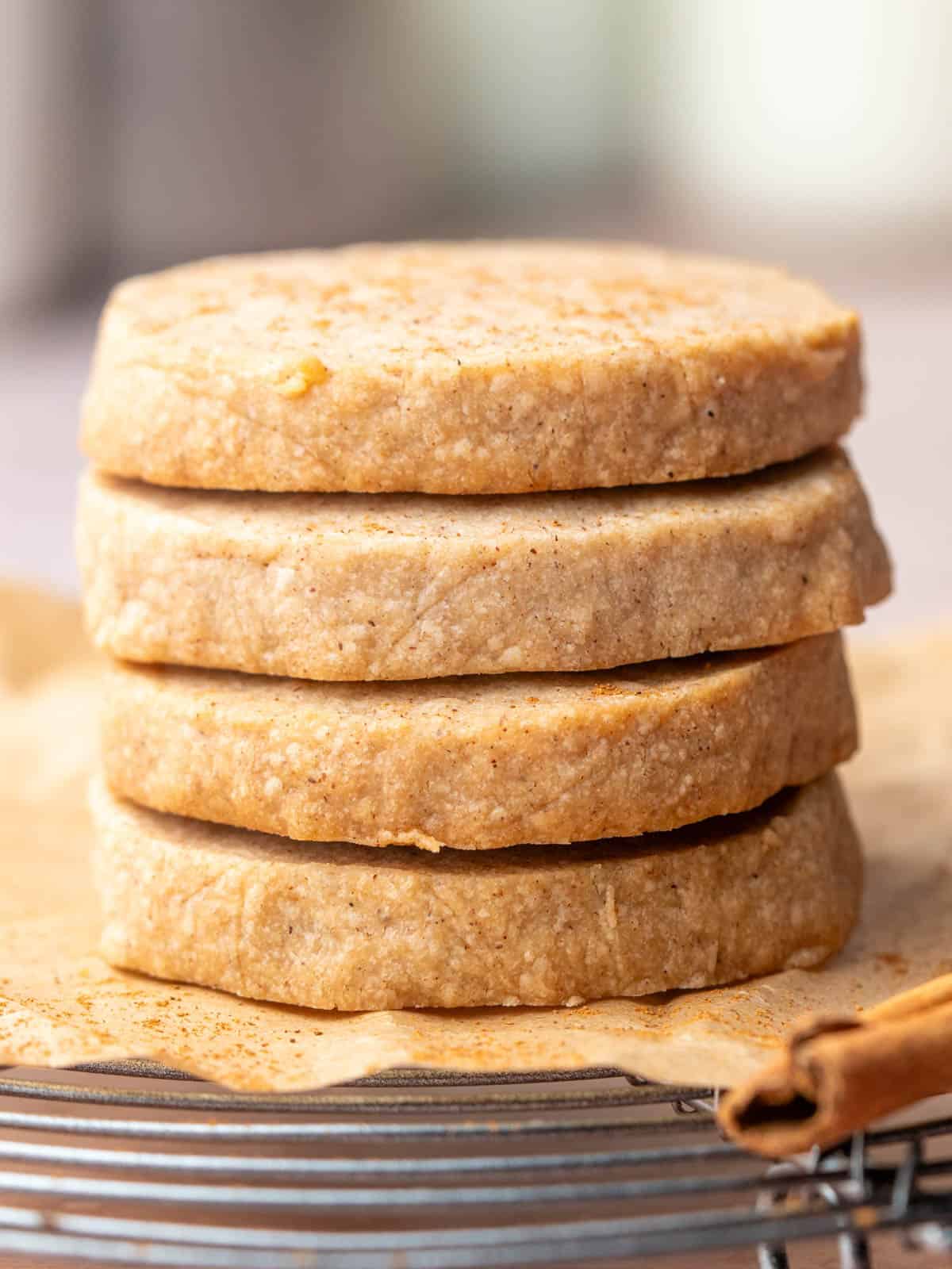 A stack of shortbread cookies with cinnamon sprinkled on top on a wire rack.
