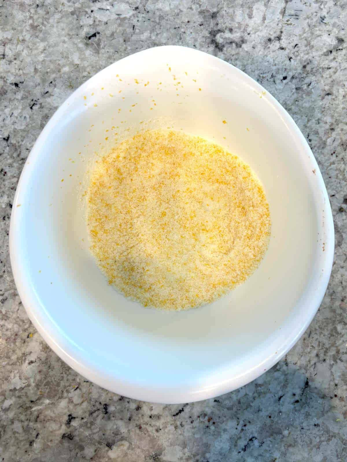 A bowl with granulated sugar and lemon zest mixed together.