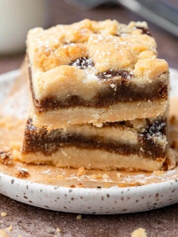 Brown sugar cinnamon bars on a plate stacked with parchment paper.