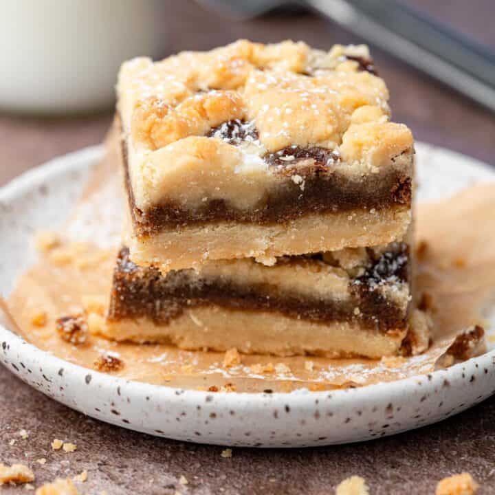 Brown sugar cinnamon bars on a plate stacked with parchment paper.