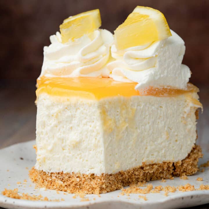 A slice of lemon curd cheesecake on a plate with a bite taken out.