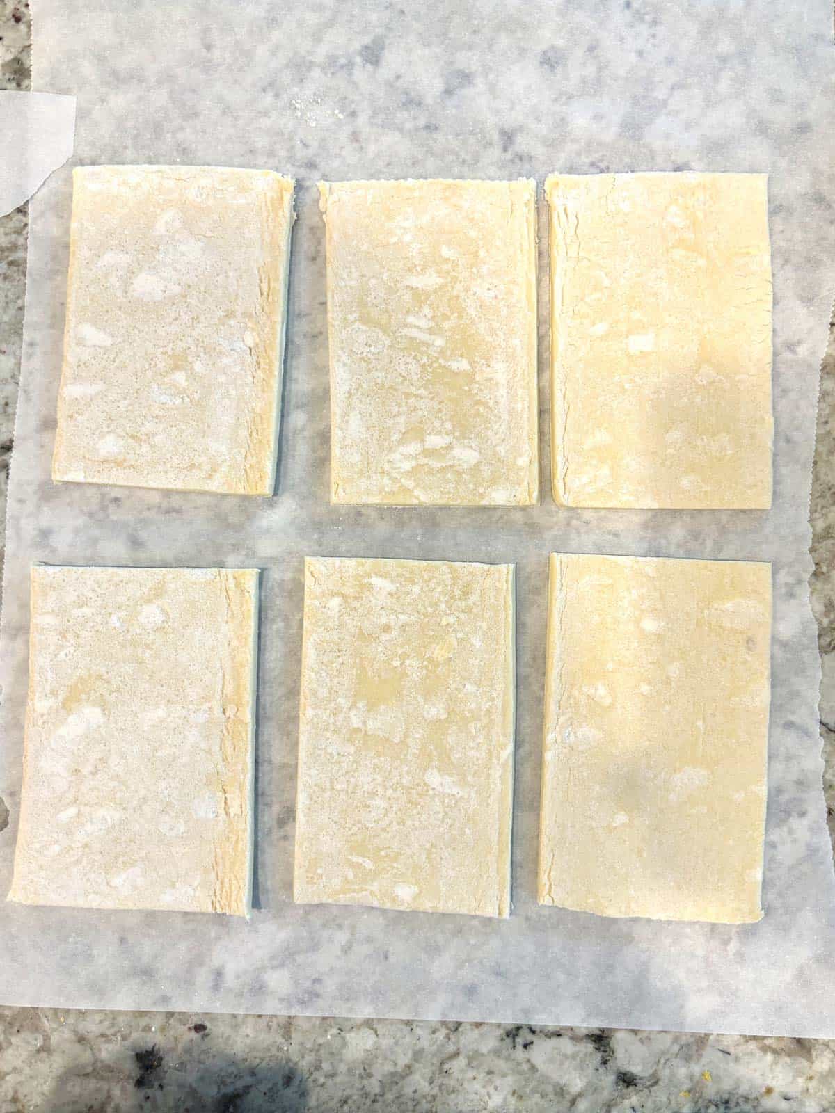 Puff pastry cut into 6 rectangles on the counter.