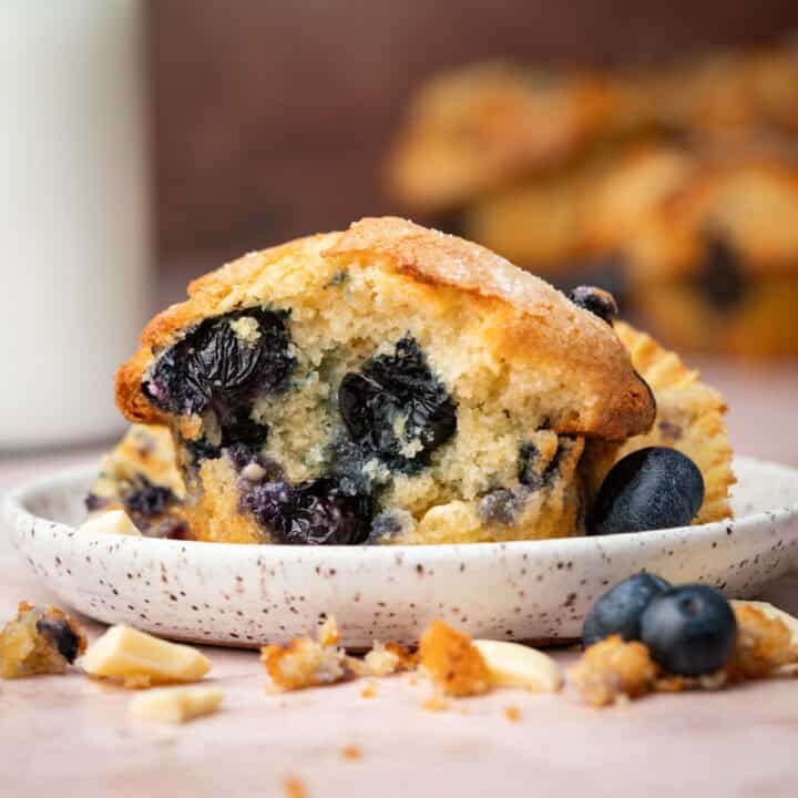 White chocolate blueberry muffins on a plate with milk in the background.