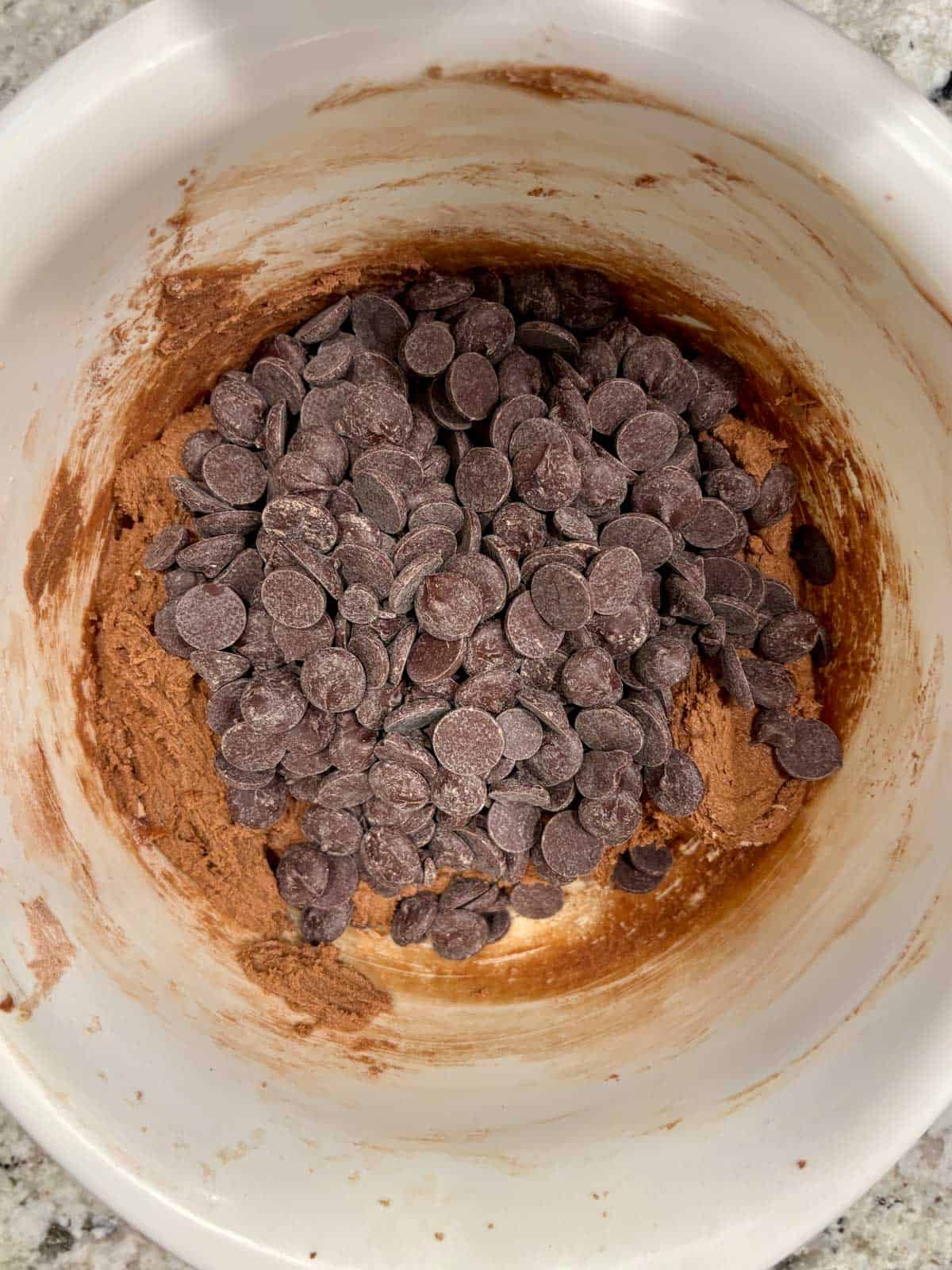 Dark chocolate chips being added to the peppermint chocolate cookie dough.