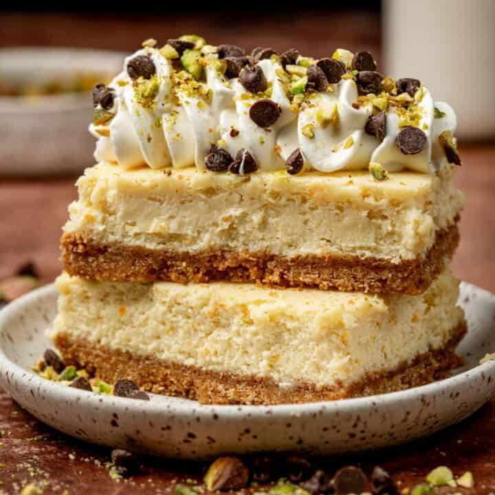 Cannoli bars stacked on top of each other showing the textures of the cheesecake.