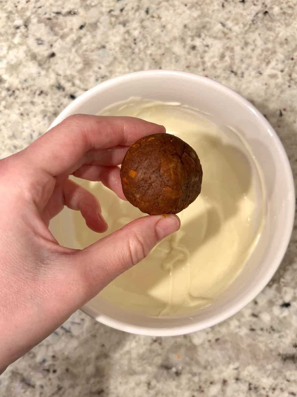 Carrot cake being rolled into balls ready to be dipped.