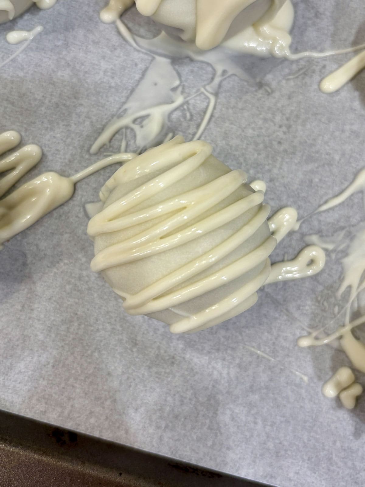 Cake truffles dipped in white chocolate with a chocolate drizzle.