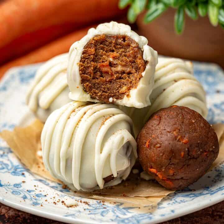 Carrot cake truffles on a plate with carrots in the background.