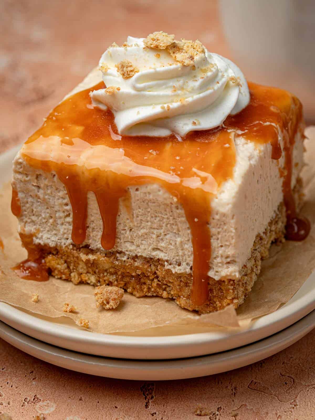 No bake cheesecake salted caramel on a plate with whipped cream on top.