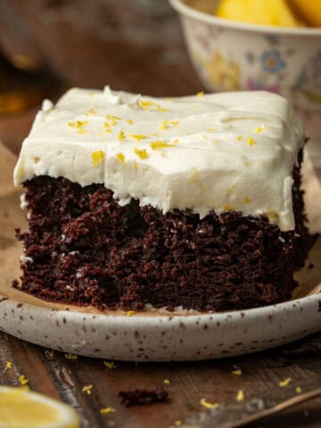 Chocolate lemon cake on a plate with lemons in the background.