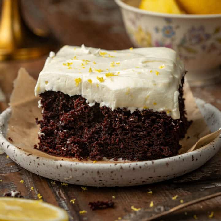 Chocolate lemon cake on a plate with lemons in the background.
