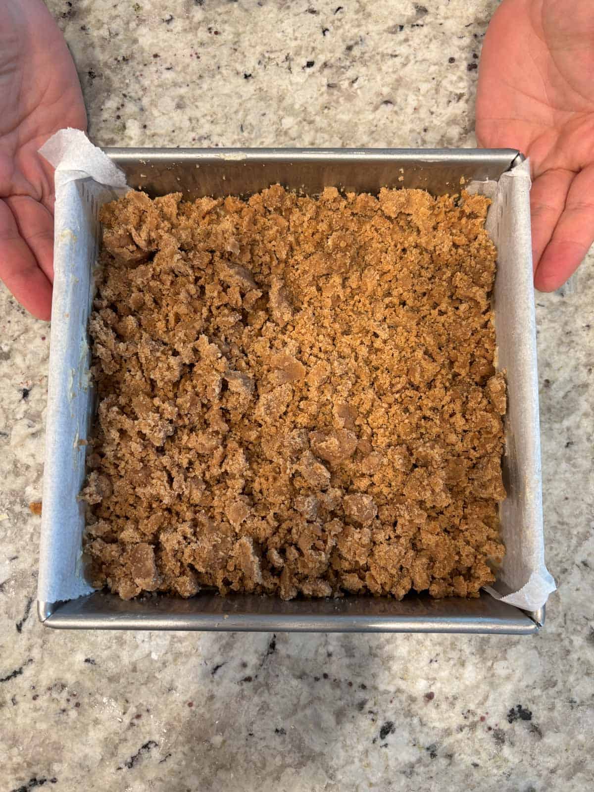 Crumb topping on top of the coffee and cardamom cake in a baking pan.