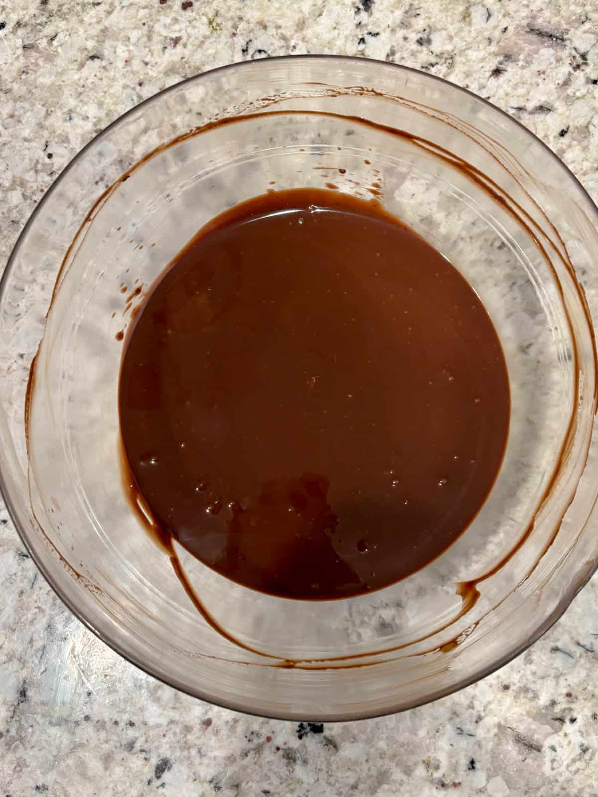 Heavy cream being poured over the chocolate and mixing until smooth.