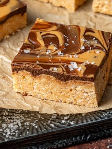 Peanut butter and chocolate krispies bars on a cookie sheet with sea salt.