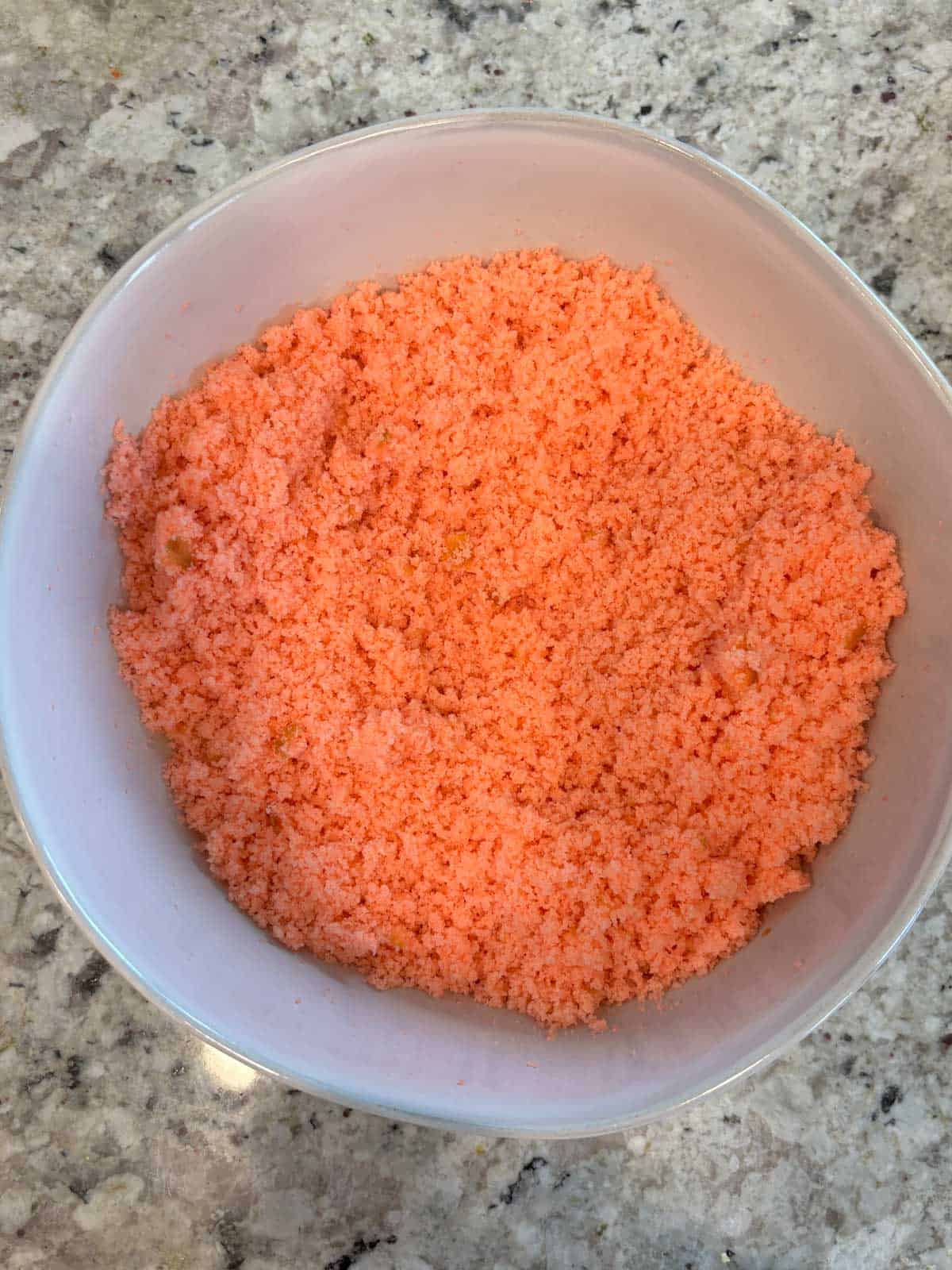 Strawberry cake broken up into crumbs in a large bowl on the counter.
