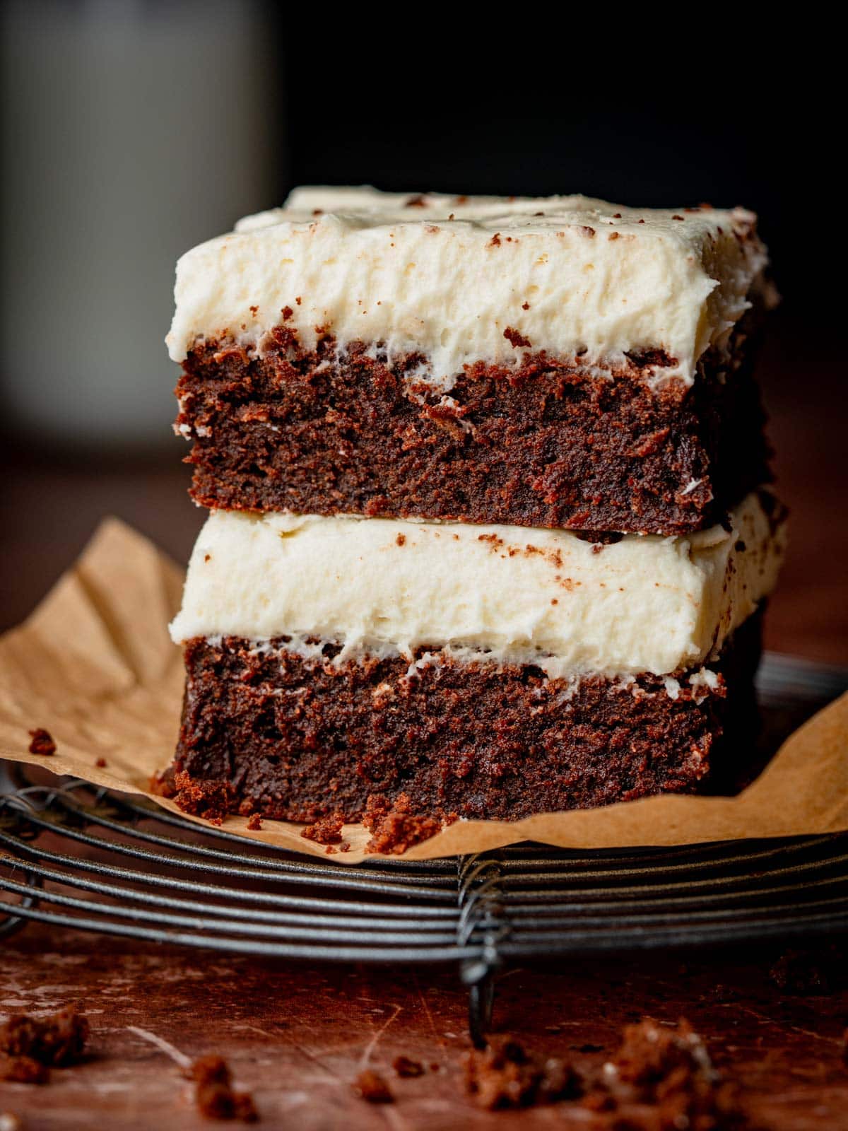Chocolate brownies with cream cheese frosting on top on a rack.