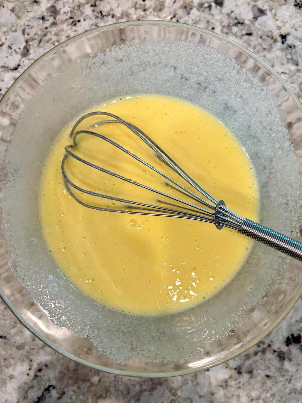 Eggs and sugar in a bowl whisked together until pale and thick.