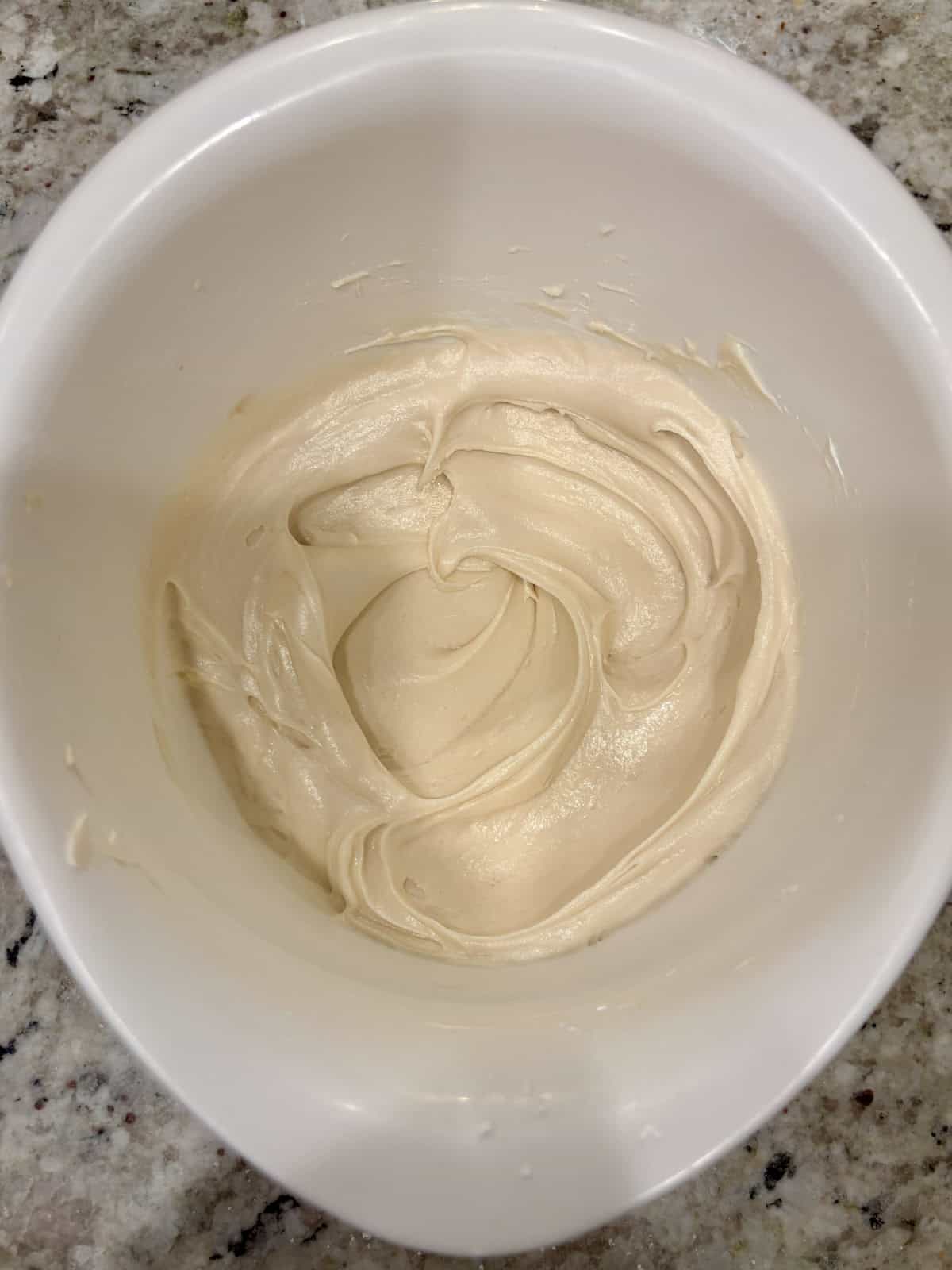 Cream cheese frosting in a bowl on the counter ready to be used.