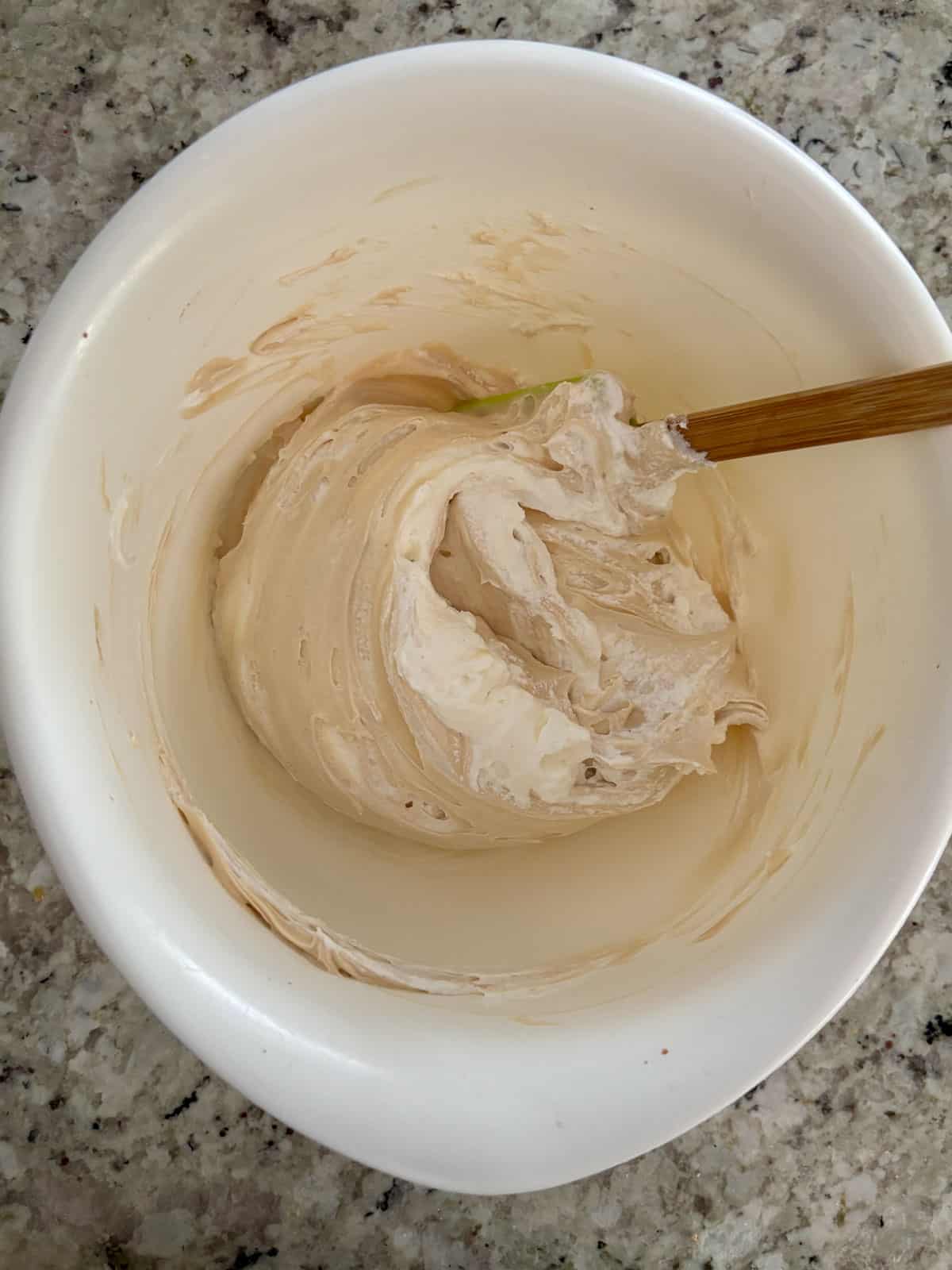 Whipped cream being folded into the caramel cream cheese mixture.