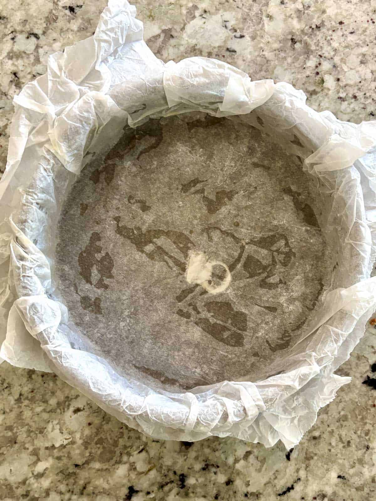 An 8 inch cake pan lined with parchment paper.