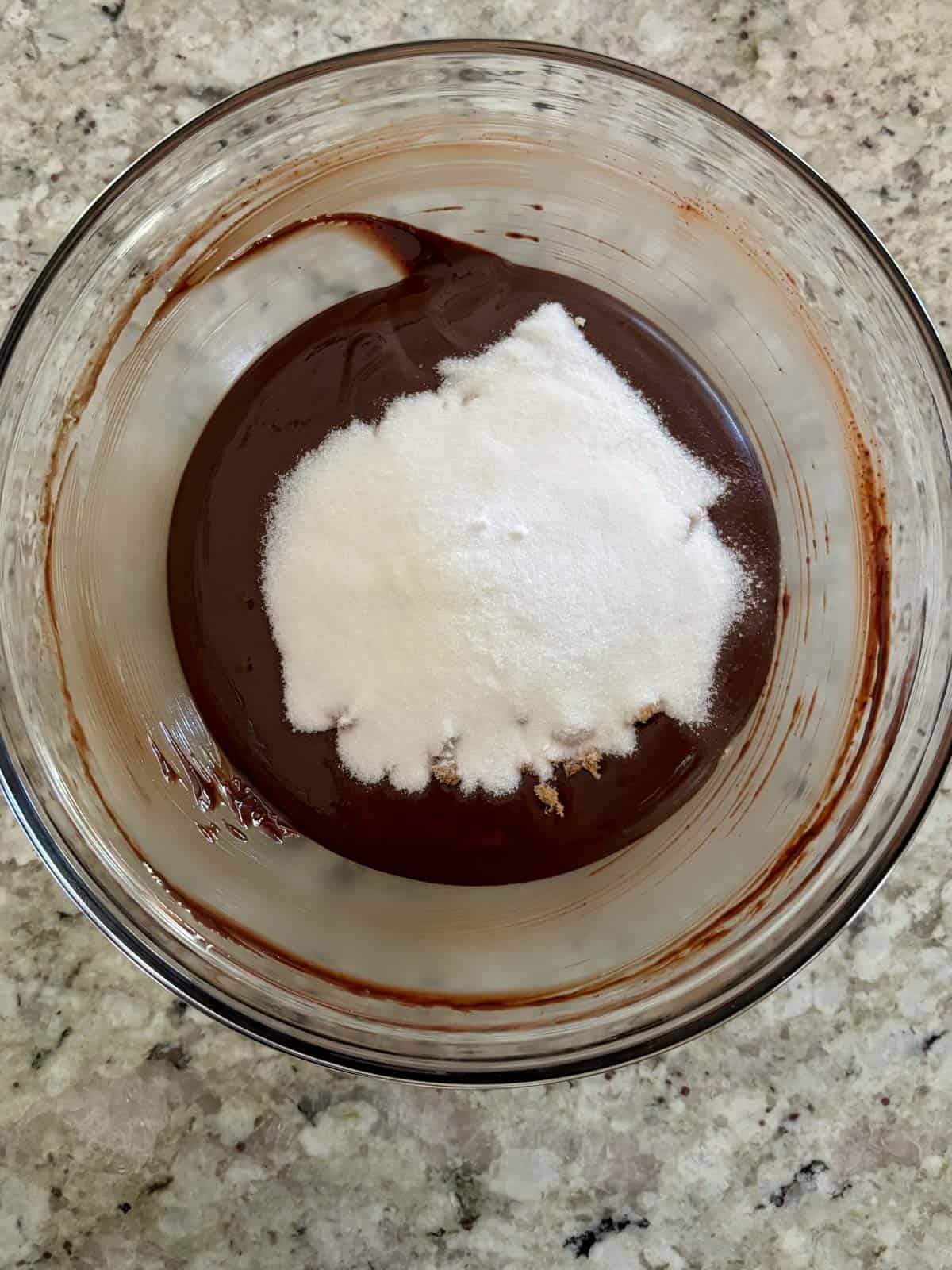 Granulated sugar being added to the butter and chocolate mixture.