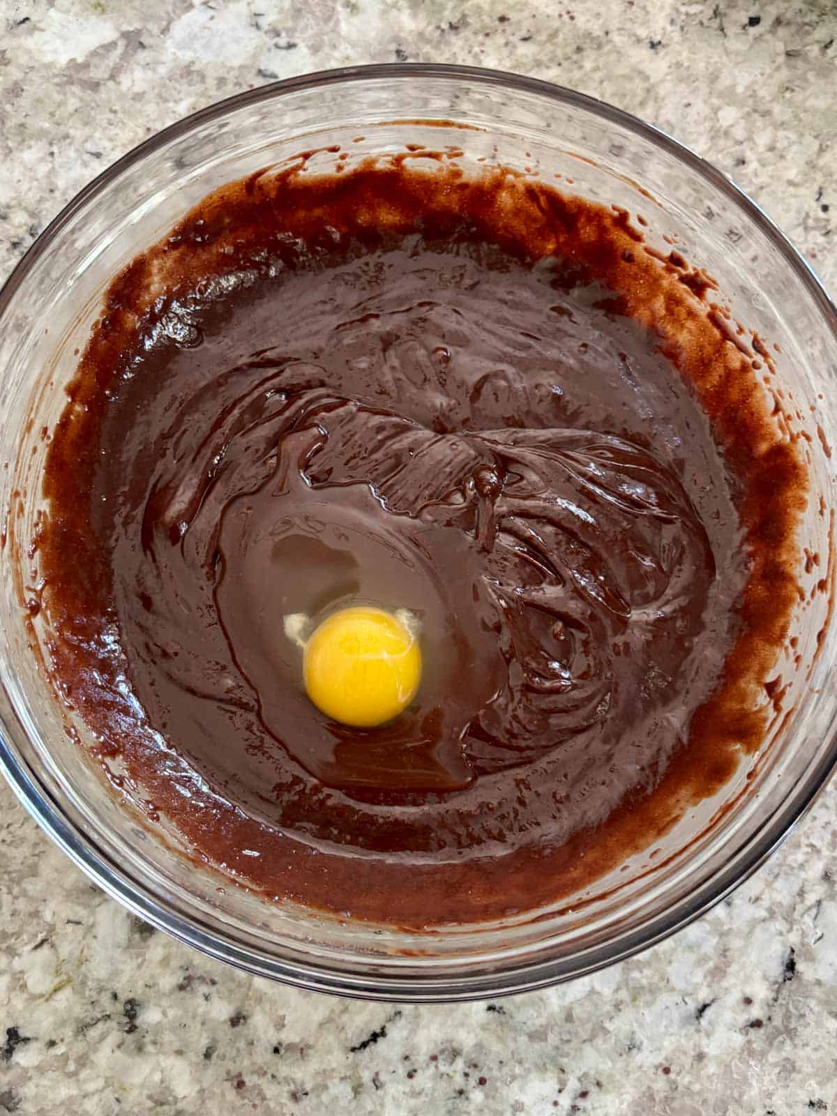 Eggs being added to the chocolate butter mixture in a bowl.
