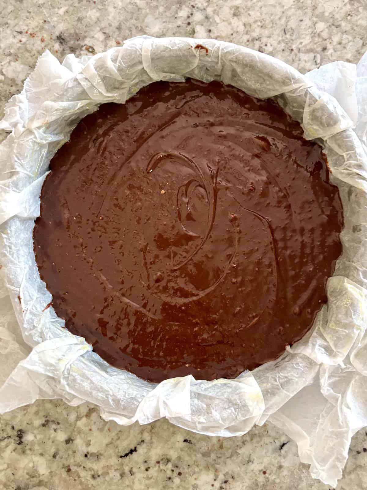The chocolate batter in the parchment lined cake pan.