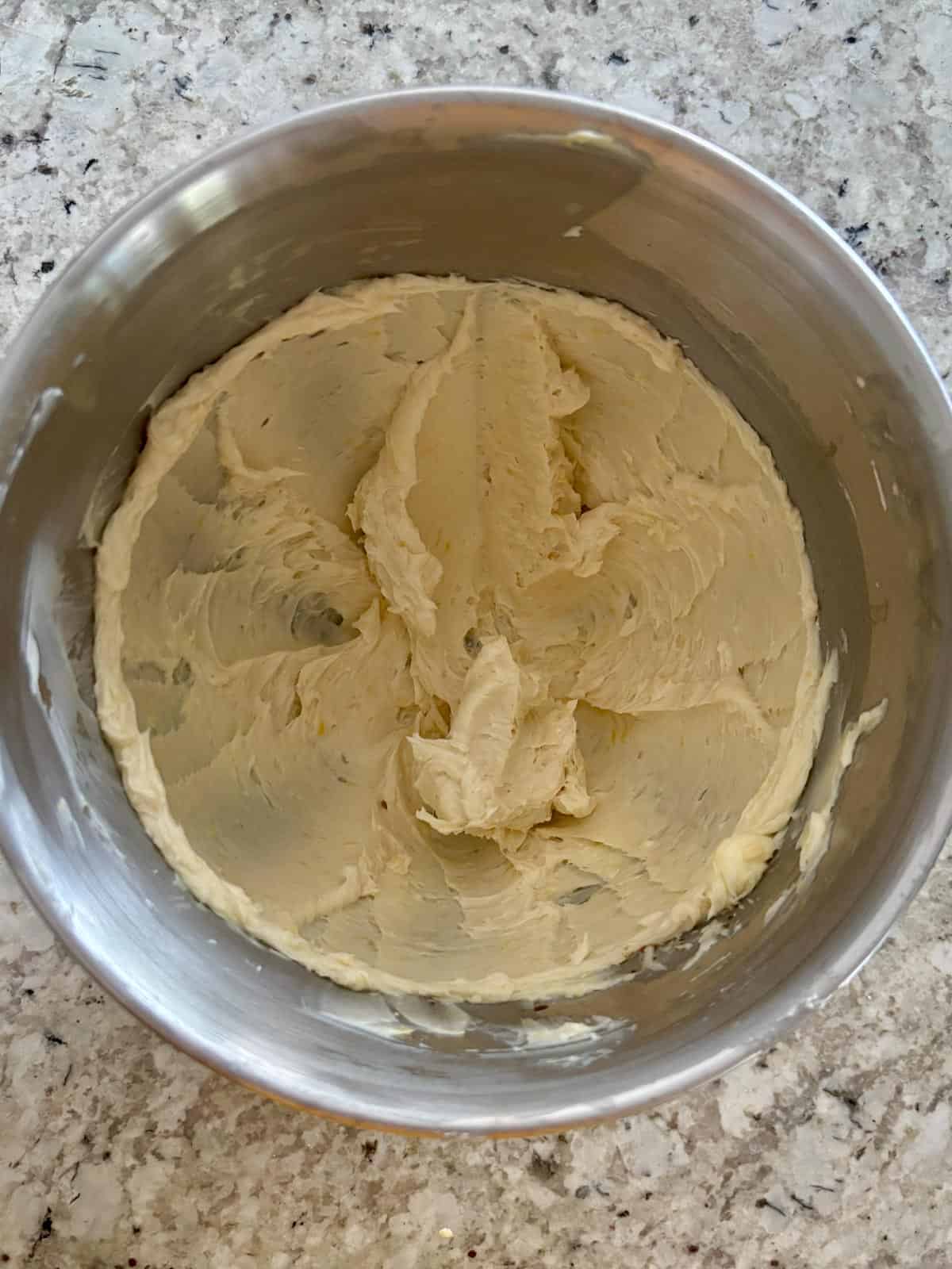 Butter, powdered sugar, lemon zest, and vanilla being mixed together in a bowl.