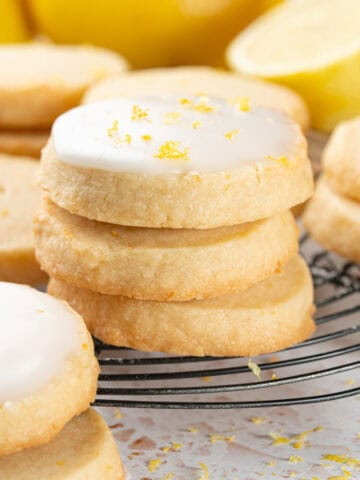 A stack of lemon cookies on a cooling rack with icing and lemon zest.