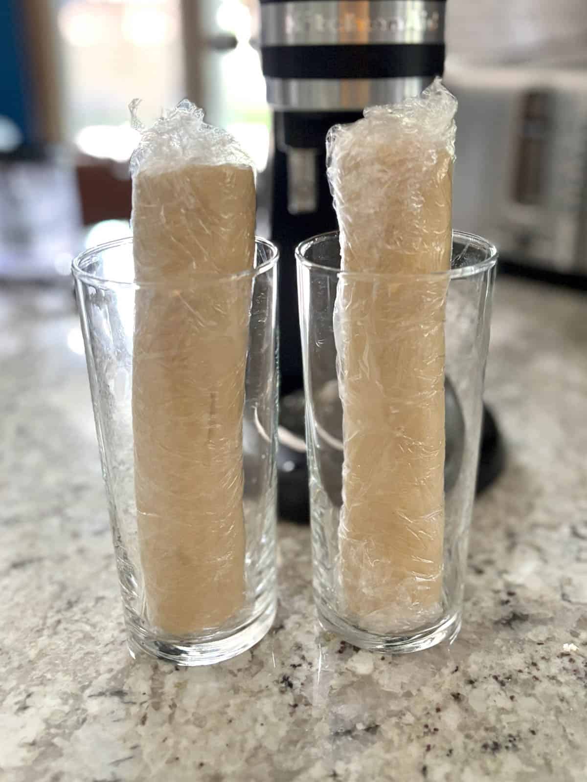 Dough logs in a glasses to prevent a dent on the side of the dough.