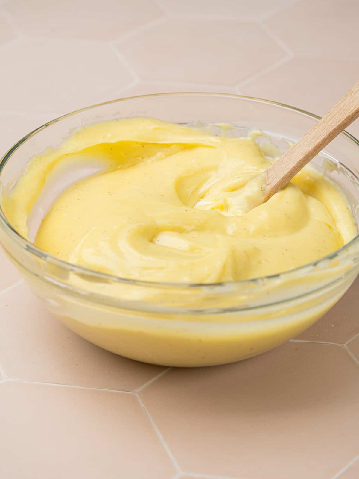 A bowl of creme patisserie with a wooden spoon.