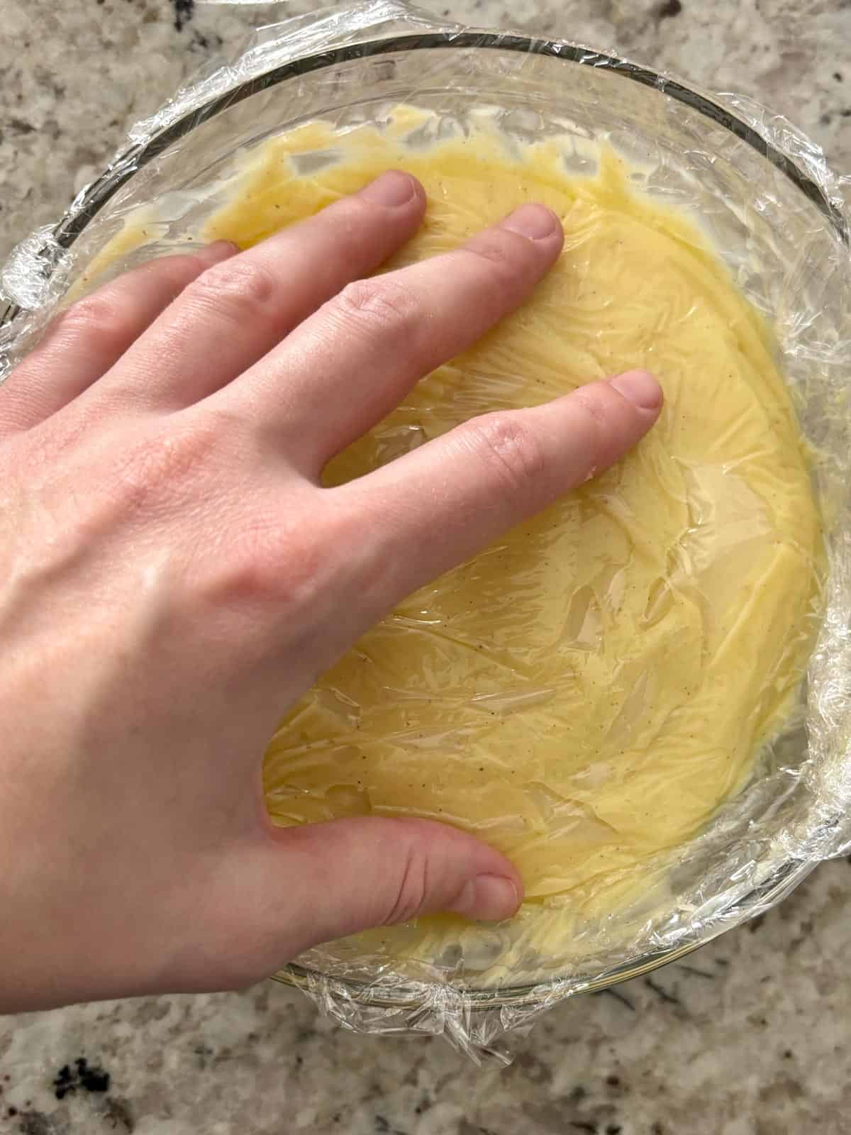 Plastic wrap being placed on the surface to prevent a skin from forming.