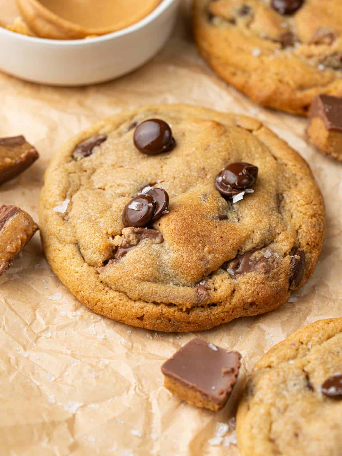 A cookie with chocolate chips and peanut butter cups on parchment paper.