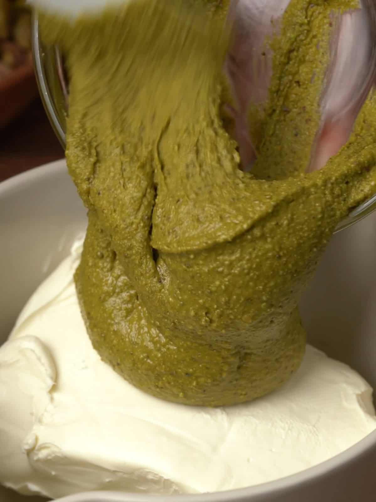 Pistachio butter going into the cream cheese mixture in a bowl.