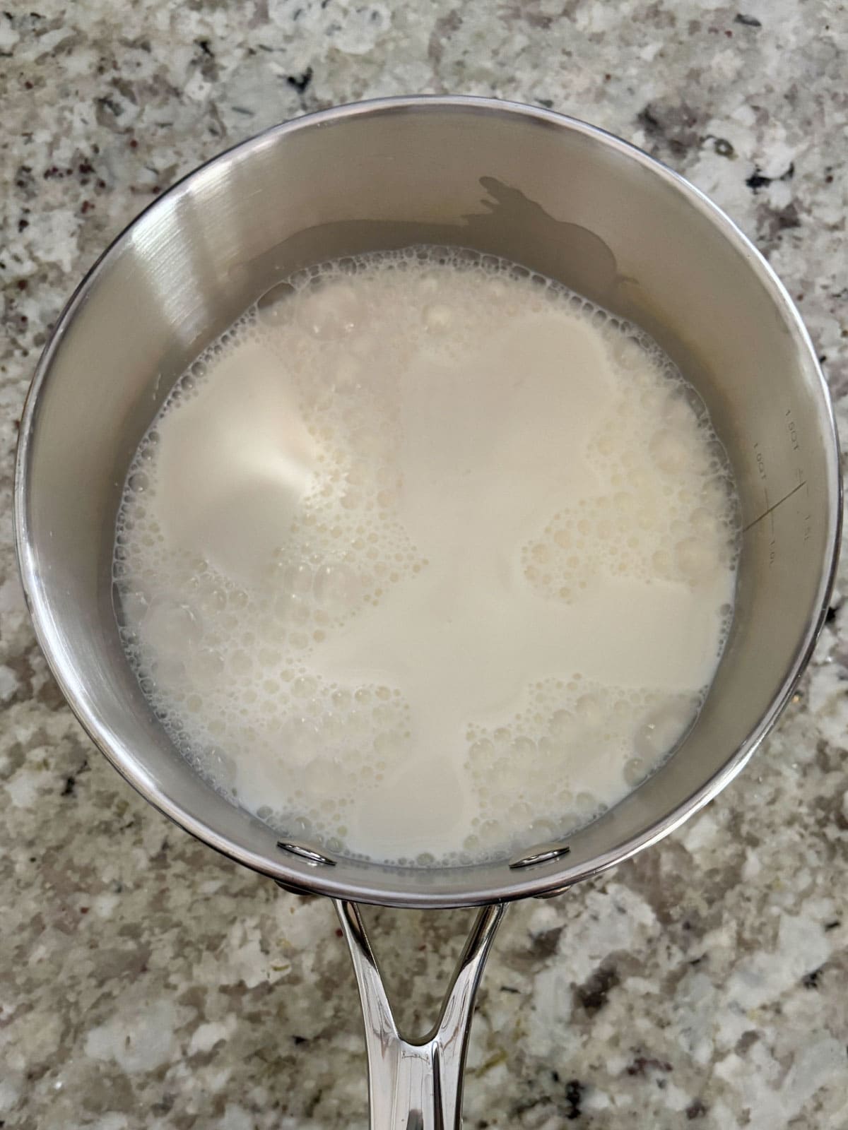 Whole milk and granulated sugar in a saucepan on the counter.