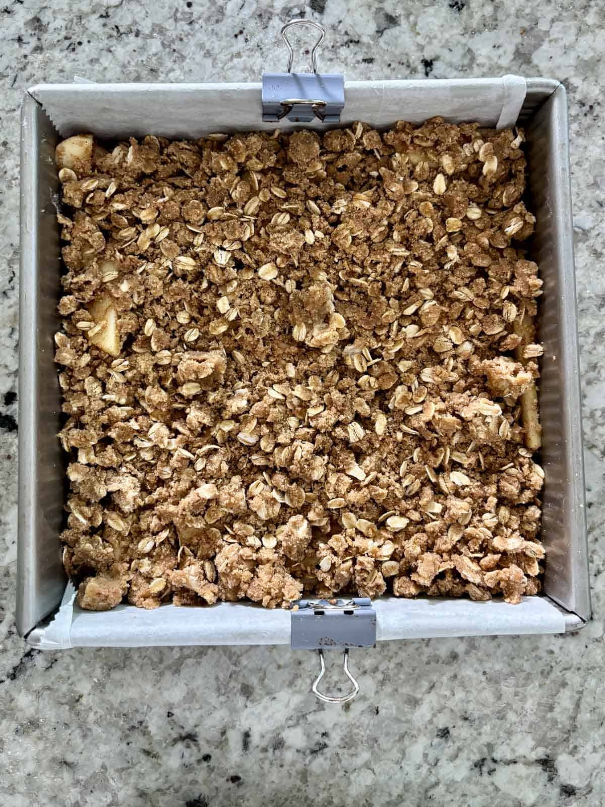 Apple crumb topping on top of sliced apples in a pan.