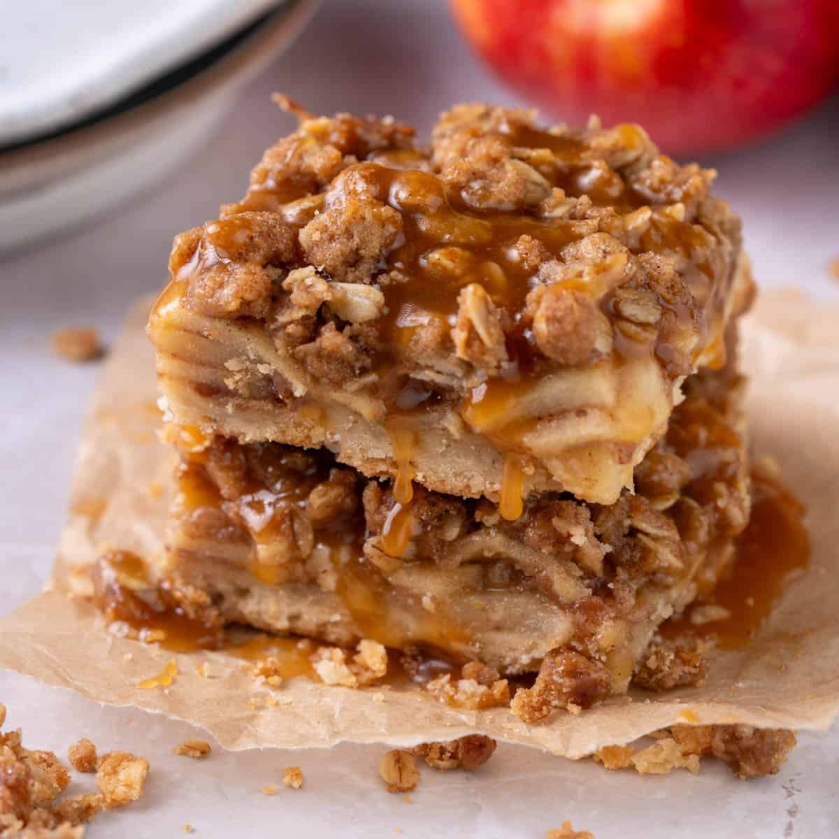 A stack of apple bars with salted caramel on top and oats around.