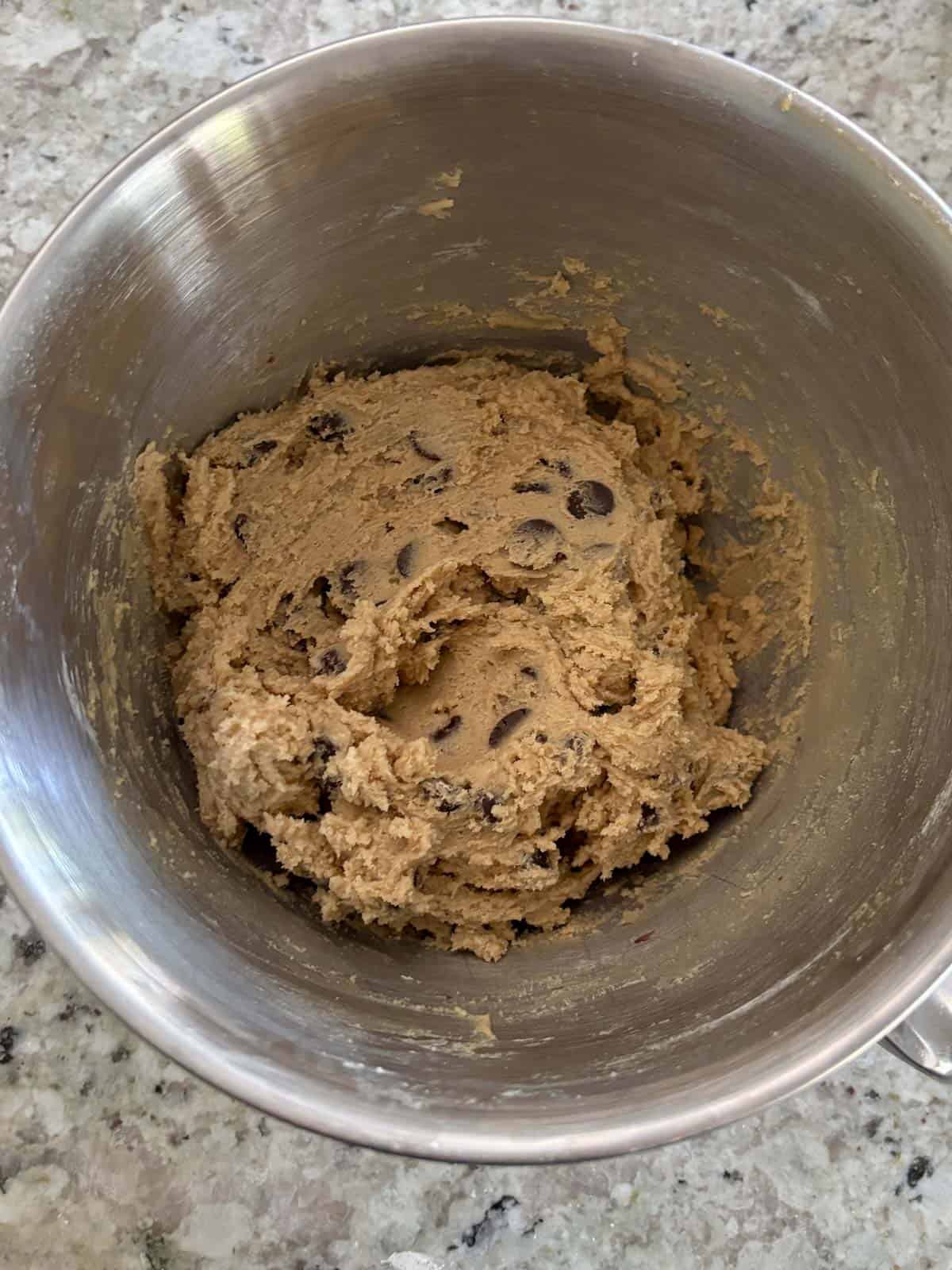Chocolate chip cookie dough in a mixing bowl on the counter.
