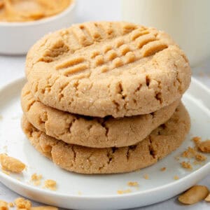 A stack of peanut butter cookies on a white plate.