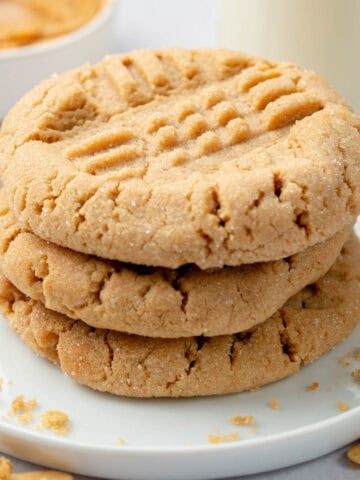 A stack of peanut butter cookies on a white plate.