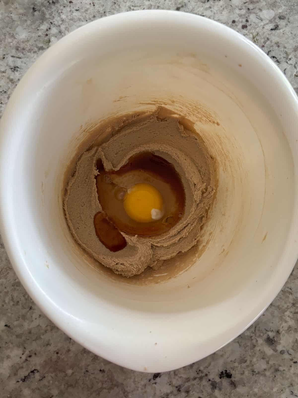 Egg and vanilla being added to the butter sugar mixture.